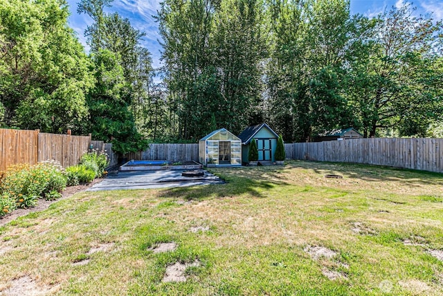 406 Brown Way SE, Orting, WA 98360 - fenced backyard featuring an outdoor structure, a greenhouse, and an outdoor fire pit