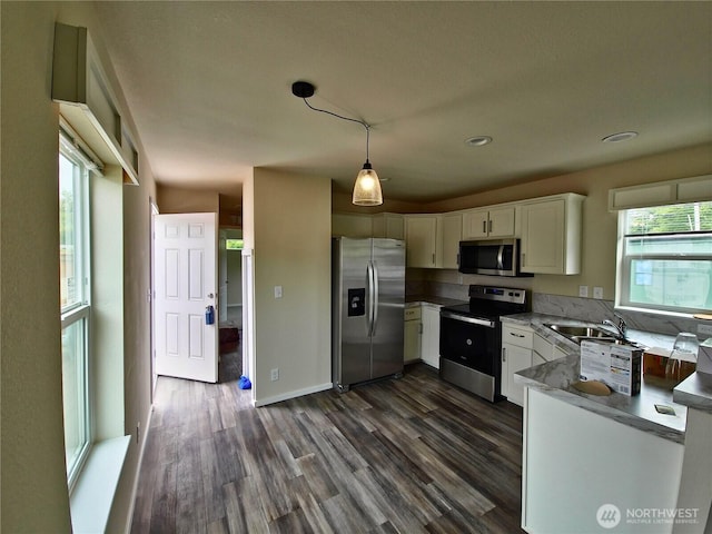 1303 30th Unit 24, Seaview, WA 98640 - kitchen featuring appliances with stainless steel finishes, dark wood-type flooring, white cabinetry, hanging light fixtures, and light countertops
