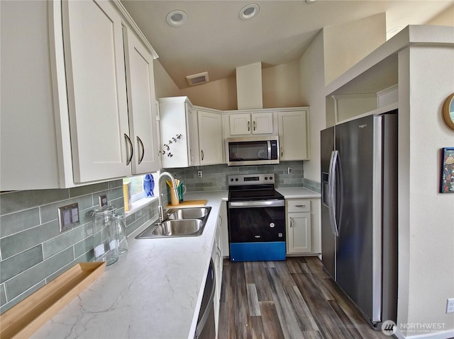 1303 30th Unit 3, Seaview, WA 98644 - kitchen with appliances with stainless steel finishes, white cabinetry, backsplash, lofted ceiling, and dark wood-style flooring