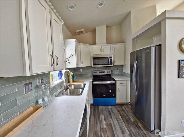 1303 30th Unit 2, Seaview, WA 98644 - kitchen with appliances with stainless steel finishes, white cabinetry, backsplash, lofted ceiling, and dark wood-style flooring