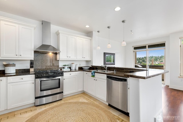 2551 Thorndyke Ave W Unit 302, Seattle, WA 98199 - kitchen with appliances with stainless steel finishes, wall chimney exhaust hood, a peninsula, recessed lighting, and decorative backsplash