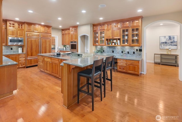 13695 NE 32nd Pl, Bellevue, WA 98005 - kitchen with built in appliances, arched walkways, brown cabinets, a large island, and recessed lighting
