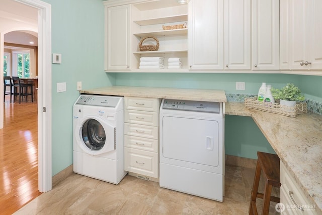 13695 NE 32nd Pl, Bellevue, WA 98005 - laundry area featuring washer and clothes dryer, arched walkways, cabinet space, and light wood finished floors