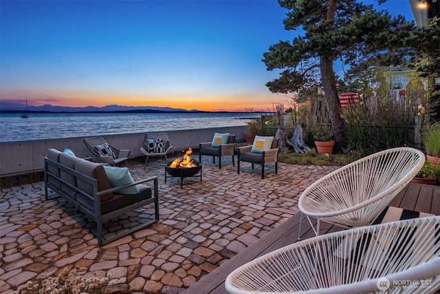 7117 Beach Dr SW, Seattle, WA 98136 - patio terrace at dusk with a patio area, a water view, and an outdoor living space with a fire pit