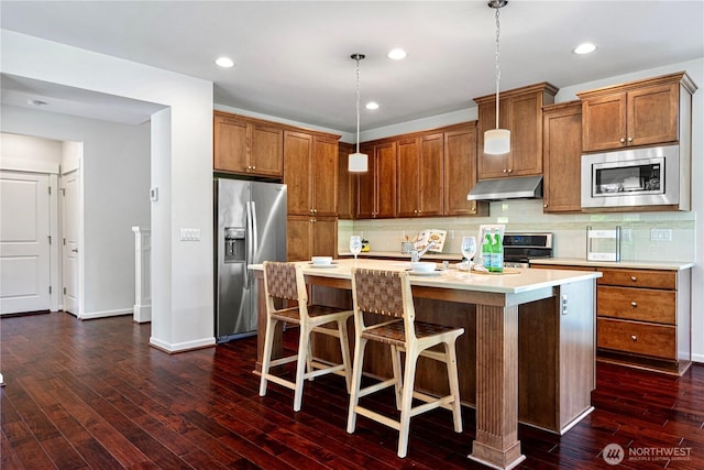 4529 185th Pl SE, Bothell, WA 98012 - kitchen featuring appliances with stainless steel finishes, under cabinet range hood, brown cabinets, light countertops, and recessed lighting