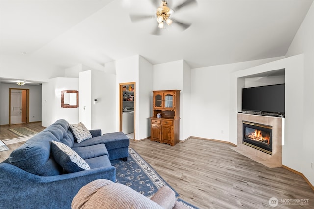 1346 Chatham Dr SE, Olympia, WA 98513 - living room featuring vaulted ceiling, ceiling fan, light wood-style flooring, a tiled fireplace, and washer / dryer