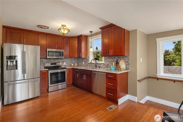 6208 Fremont Ave N, Seattle, WA 98103 - kitchen featuring stainless steel appliances, backsplash, light wood-style flooring, and plenty of natural light