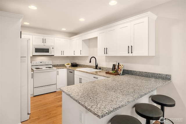 17515 110th Ln SE Unit 27, Renton, WA 98055 - kitchen featuring white appliances, white cabinets, a peninsula, recessed lighting, and a kitchen bar
