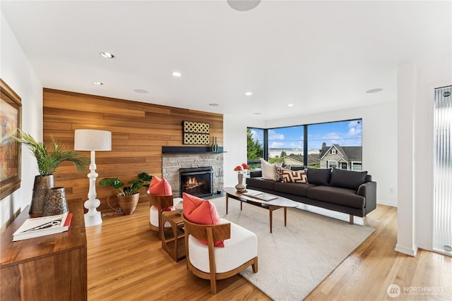 2626 W Lynn St, Seattle, WA 98199 - living area featuring a stone fireplace, light wood-type flooring, recessed lighting, and wood walls