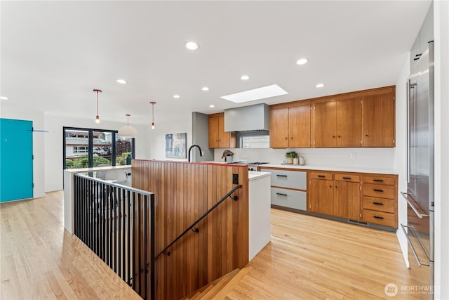2626 W Lynn St, Seattle, WA 98199 - kitchen featuring a skylight, light wood finished floors, brown cabinetry, high end fridge, and light countertops
