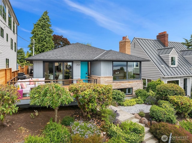 2626 W Lynn St, Seattle, WA 98199 - back of property with a standing seam roof, a chimney, a metal roof, roof with shingles, and stone siding