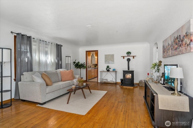 7012 S Warner St, Tacoma, WA 98409 - living room featuring light wood-style flooring, a wood stove, and arched walkways