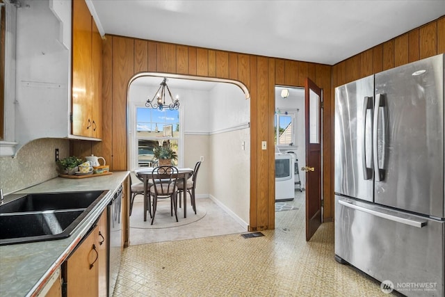 7012 S Warner St, Tacoma, WA 98409 - kitchen featuring appliances with stainless steel finishes, brown cabinetry, a chandelier, and wood walls