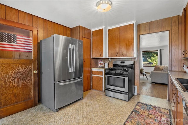 7012 S Warner St, Tacoma, WA 98409 - kitchen with appliances with stainless steel finishes, brown cabinets, light countertops, and wooden walls