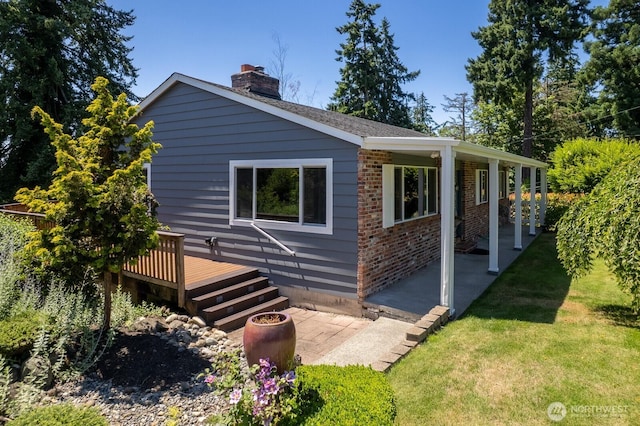 10414 43rd Street Ct E, Edgewood, WA 98372 - view of property exterior with a patio, a chimney, brick siding, a wooden deck, and a yard
