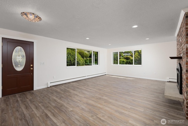 10414 43rd Street Ct E, Edgewood, WA 98372 - entrance foyer with a baseboard radiator, a textured ceiling, a brick fireplace, wood finished floors, and recessed lighting