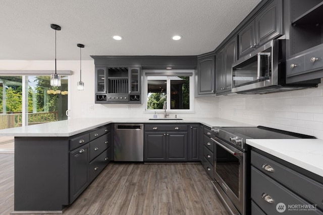 10414 43rd Street Ct E, Edgewood, WA 98372 - kitchen with stainless steel appliances, a peninsula, dark wood finished floors, tasteful backsplash, and a textured ceiling