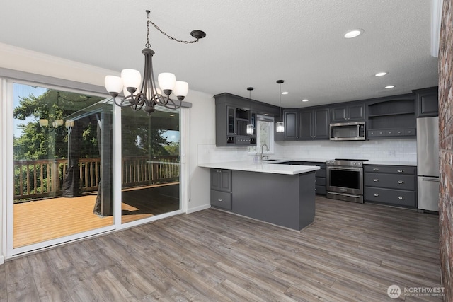 10414 43rd Street Ct E, Edgewood, WA 98372 - kitchen featuring stainless steel appliances, open shelves, a peninsula, a chandelier, and decorative backsplash