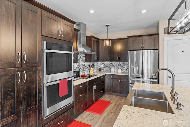 22817 80th Avenue Ct E, Graham, WA 98338 - kitchen featuring appliances with stainless steel finishes, wall chimney exhaust hood, light wood-type flooring, dark brown cabinetry, and tasteful backsplash