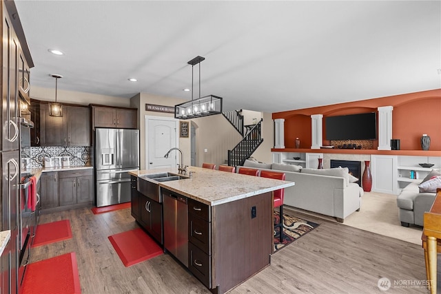 22817 80th Avenue Ct E, Graham, WA 98338 - kitchen with stainless steel appliances, dark brown cabinets, wood finished floors, an island with sink, and pendant lighting