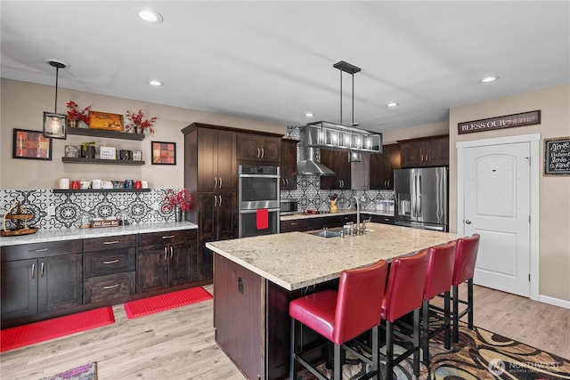 22817 80th Avenue Ct E, Graham, WA 98338 - kitchen with appliances with stainless steel finishes, tasteful backsplash, light wood-type flooring, a kitchen breakfast bar, and recessed lighting