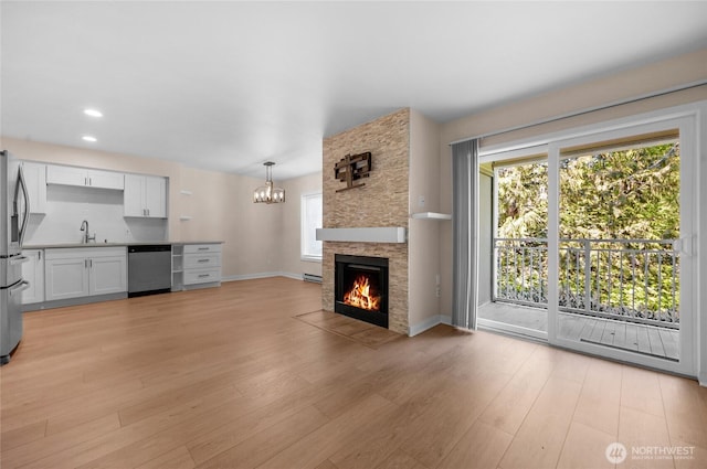 12303 Harbour Pointe Blvd Unit S104, Mukilteo, WA 98275 - unfurnished living room with a chandelier, light wood finished floors, a fireplace, recessed lighting, and a baseboard heating unit