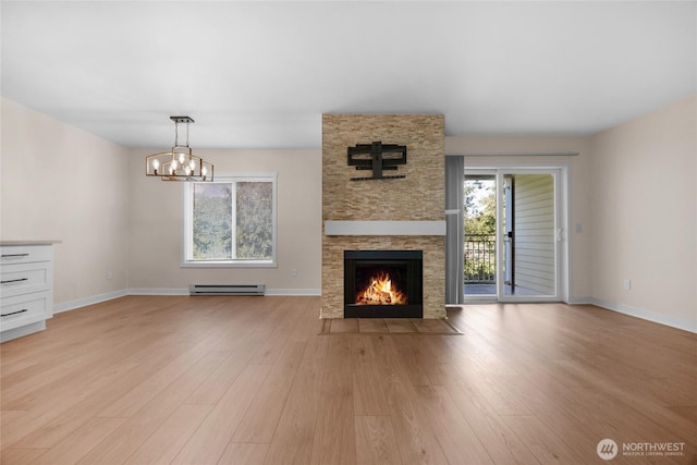 12303 Harbour Pointe Blvd Unit S104, Mukilteo, WA 98275 - unfurnished living room featuring a baseboard radiator, light wood-style floors, a stone fireplace, and a chandelier