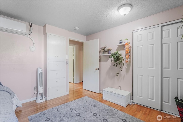 2120 Seaview St W, University Place, WA 98466 - bedroom featuring a wall unit AC, a textured ceiling, light wood finished floors, and a closet