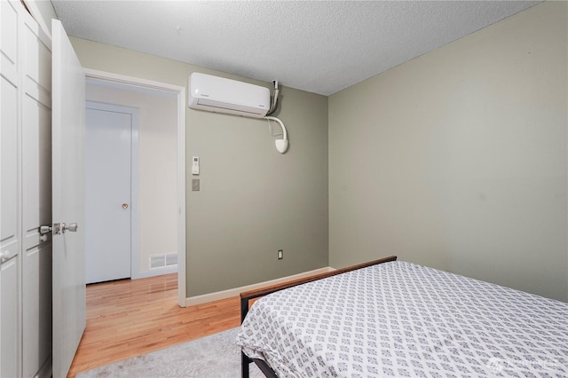 2120 Seaview St W, University Place, WA 98466 - bedroom featuring a wall unit AC, light wood-style flooring, and a textured ceiling
