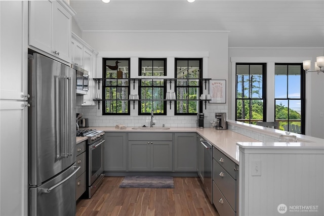 46 Seaside Ln, Pacific Beach, WA 98571 - kitchen with high end appliances, a peninsula, dark wood finished floors, light countertops, and decorative backsplash