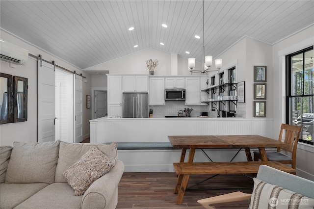 46 Seaside Ln, Pacific Beach, WA 98571 - kitchen with stainless steel appliances, a barn door, wood finished floors, lofted ceiling, and a wall mounted air conditioner
