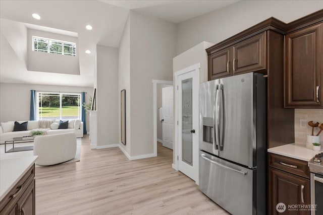 250 W Wynwood Dr, Shelton, WA 98584 - kitchen featuring stainless steel refrigerator with ice dispenser, light wood-type flooring, light countertops, open floor plan, and high vaulted ceiling