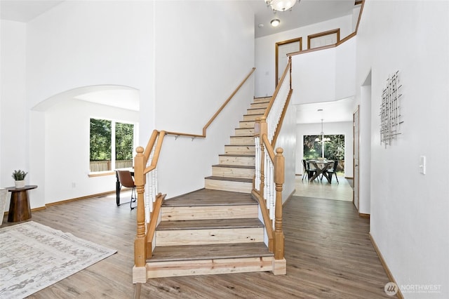 21012 82nd St E, Bonney Lake, WA 98391 - staircase featuring arched walkways, a towering ceiling, wood finished floors, and a chandelier