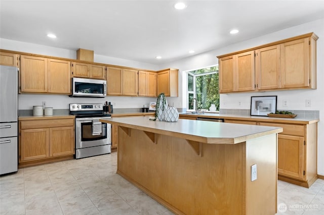21012 82nd St E, Bonney Lake, WA 98391 - kitchen featuring appliances with stainless steel finishes, a kitchen island, light countertops, recessed lighting, and a breakfast bar area