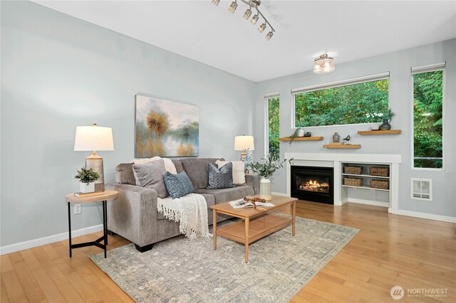 15150 140th Way SE Unit K103, Renton, WA 98058 - living room with hardwood / wood-style floors, plenty of natural light, and a warm lit fireplace