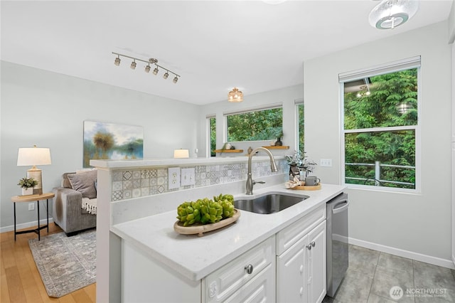 15150 140th Way SE Unit K103, Renton, WA 98058 - kitchen featuring dishwasher, white cabinetry, open floor plan, light stone counters, and rail lighting