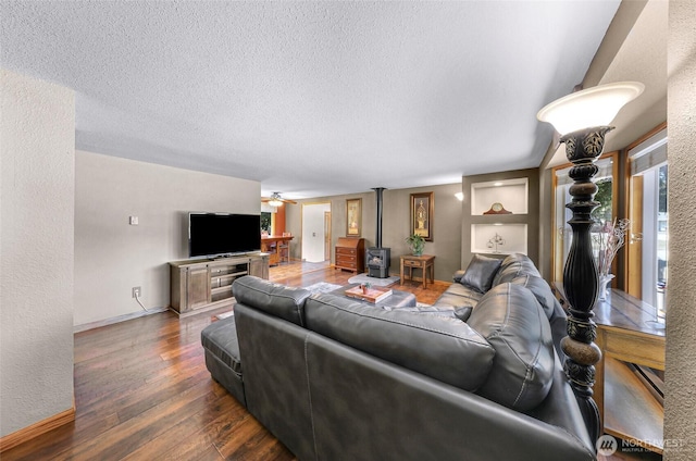 5215 Richmond Cres, Blaine, WA 98230 - living room featuring a ceiling fan, a wood stove, wood finished floors, a textured ceiling, and built in shelves