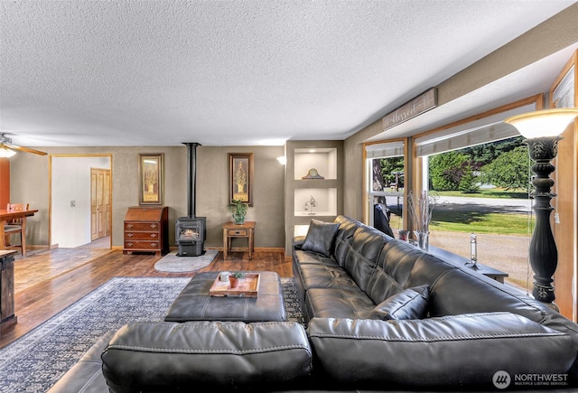 5215 Richmond Cres, Blaine, WA 98230 - living area featuring wood finished floors, a textured ceiling, a wood stove, and a ceiling fan