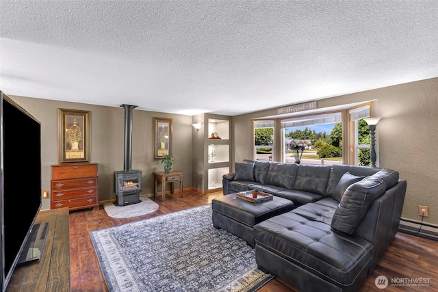 5215 Richmond Cres, Blaine, WA 98230 - living area featuring a textured ceiling, wood finished floors, a wood stove, a textured wall, and a baseboard radiator