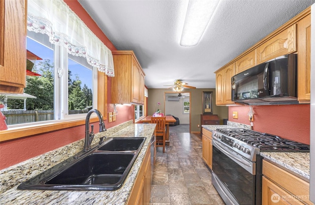5215 Richmond Cres, Blaine, WA 98230 - kitchen with gas range, black microwave, ceiling fan, stone finish flooring, and light stone counters