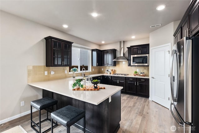 6639 S 298th Pl, Auburn, WA 98001 - kitchen featuring appliances with stainless steel finishes, wall chimney exhaust hood, a peninsula, a kitchen bar, and tasteful backsplash