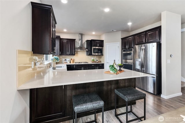 6639 S 298th Pl, Auburn, WA 98001 - kitchen with appliances with stainless steel finishes, wall chimney exhaust hood, light countertops, a peninsula, and light wood-style flooring