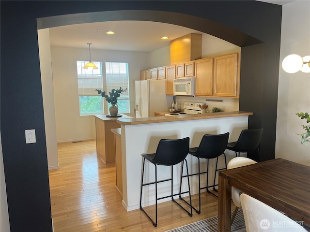 21507 42nd Ave S Unit P3, Seatac, WA 98198 - kitchen featuring white appliances, a peninsula, light wood-style flooring, light brown cabinetry, and arched walkways