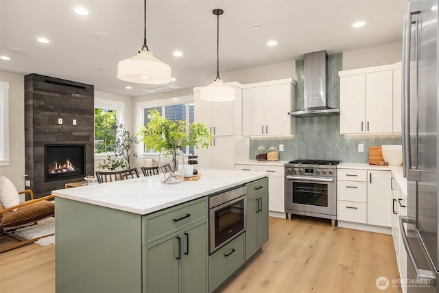 10511 NE 112th St, Kirkland, WA 98033 - kitchen featuring green cabinets, a large fireplace, white cabinets, wall chimney exhaust hood, and light wood-type flooring