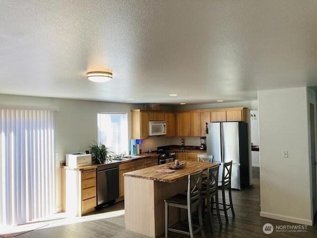 2020 Perch Ave, Moses Lake, WA 98837 - kitchen featuring stainless steel appliances, a center island, a kitchen breakfast bar, dark wood-style flooring, and wood counters