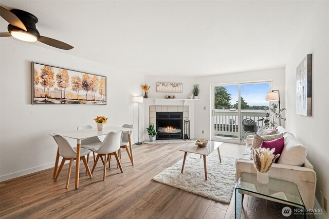 411 N 90th St Unit 406, Seattle, WA 98103 - living room featuring wood finished floors, a tiled fireplace, and ceiling fan