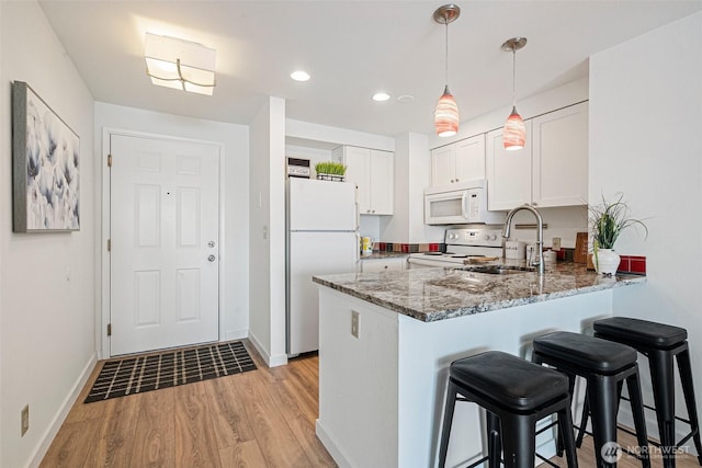 411 N 90th St Unit 406, Seattle, WA 98103 - kitchen featuring white appliances, a peninsula, light stone countertops, light wood-style floors, and white cabinets