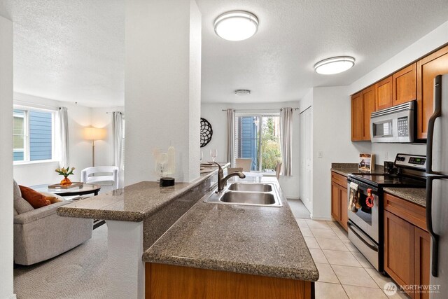 300 10th Ave Unit B310, Seattle, WA 98122 - kitchen featuring appliances with stainless steel finishes, a textured ceiling, brown cabinets, dark countertops, and a peninsula