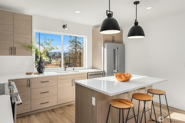 333 NW 47th St Unit B, Seattle, WA 98107 - kitchen with appliances with stainless steel finishes, a breakfast bar, light brown cabinets, modern cabinets, and recessed lighting