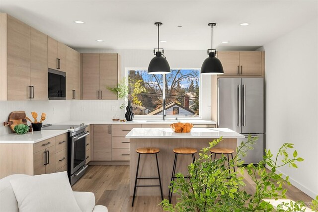 333 NW 47th St Unit B, Seattle, WA 98107 - kitchen with stainless steel appliances, a breakfast bar area, light wood finished floors, light countertops, and a center island